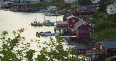 Geleneksel kırmızı kulübeler veya Reine-Lofoten Adaları 'ndaki göl kenarındaki balıkçı kulübeleri. Sabahın erken saatlerinde, bulutlu bir günde. Kıyıya demirlemiş tekneler