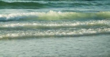 Dalgalar deniz kıyısına yaklaşıyor. Turkuaz okyanus, kumsala ulaşan dalgaların rahatlatıcı manzarası.. 
