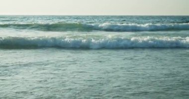 Dalgalar deniz kıyısına yaklaşıyor. Turkuaz okyanus, kumsala ulaşan dalgaların rahatlatıcı manzarası.. 