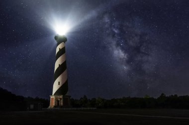 Amerika 'nın en uzun deniz feneri olan Kuzey Carolina' nın dış kıyılarındaki Cape Hatteras Işığı Samanyolu 'nun galaktik merkezi ile yıldızlı yaz gecesi gökyüzünde parlar..
