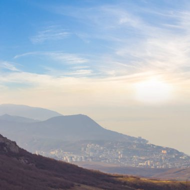 view from mountain ridge to the small town on sea bay coast at the sunset