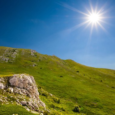 green mountain under a sparkle sun, green grass and stones outdoor mountain landscape