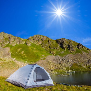 small touristic tent stay on mountain lake coast at sunny day, mountain travel background