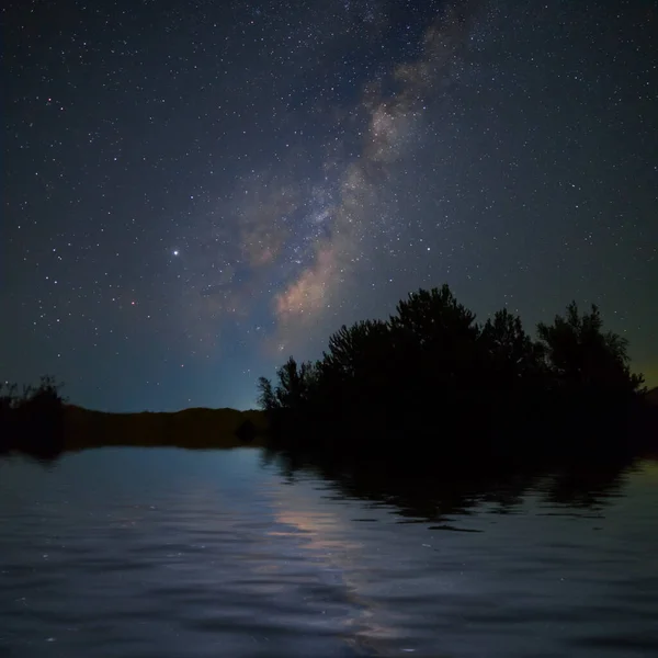 Sakin Göle Yansıyan Samanyolu Ile Yıldızlı Gökyüzünün Altındaki Orman Silueti — Stok fotoğraf