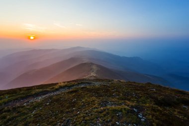 Dağ vadisi, güneşin doğuşunda yoğun bir sis içinde, sabahın erken saatlerinde dağ manzarası.