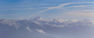 Yoğun bulutlu gökyüzünün altında karlı dağ sırtı