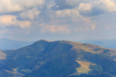 Bulutlu bir gökyüzünün altında yaz dağı zinciri