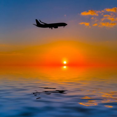 Gün batımında suyun üzerinde uçan uçak silueti, hava taşımacılığı arka planı