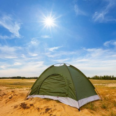 Kumlu çayırlar arasında küçük yeşil turistik çadır, yaz tatili arka planı