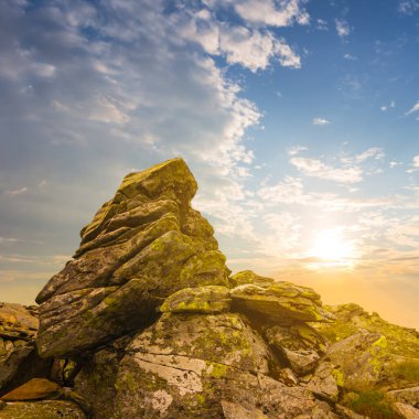 Dramatik günbatımında tek başına kayalık dağın tepesinde 