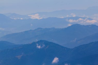 Dağ sırtı silueti mavi sisli, sabahın erken saatlerinde dağ arka planında