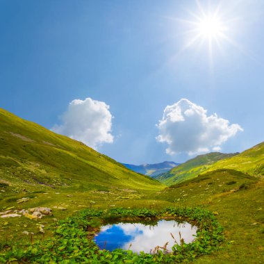 Yazın güneşli bir günde küçük gölü olan yeşil dağ vadisi, güzel bir dağ yolculuğu geçmişi.
