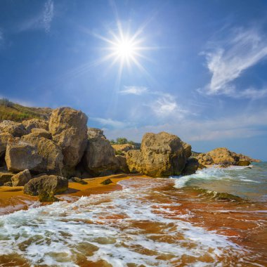 Deniz dalgaları güneşli bir günde kayalık kıyılara vurur.