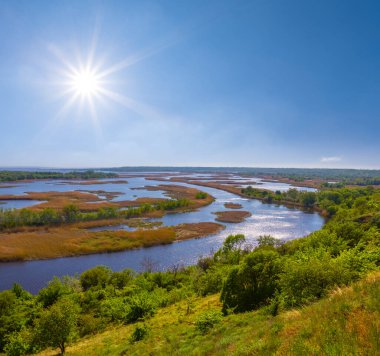 Sakin nehir delta akıntısı parlayan güneşin altında çayırların arasında