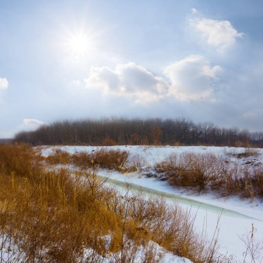 Güneşli kış gününde donmuş karlı bir nehir.