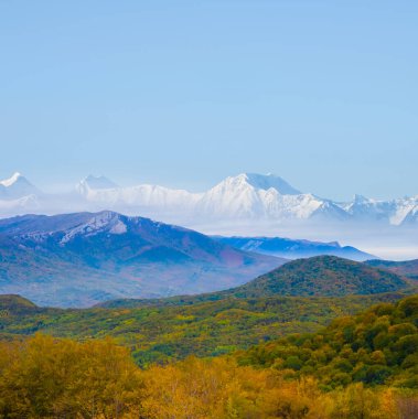 Kızıl ormanlı sonbahar vadisi ve karlı dağ zinciri