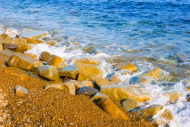 Kumlu deniz sahilinde yakın çekim taşları, yaz mevsimi arka planı.