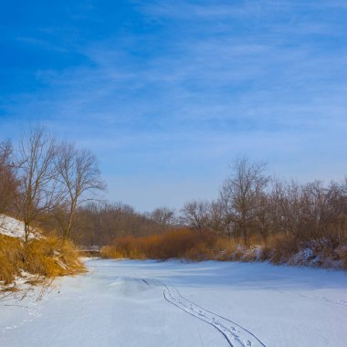 Donmuş kış nehri mavi bulutlu bir gökyüzünün altında