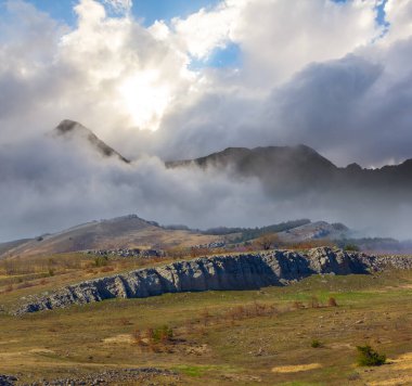 Yoğun sisli dağ vadisi ve gün batımında bulutlar