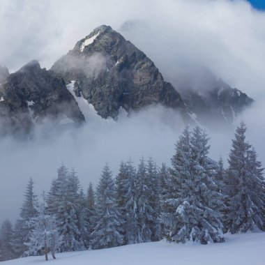 Yoğun sis ve bulutlarda karlı kayalık dağ zinciri