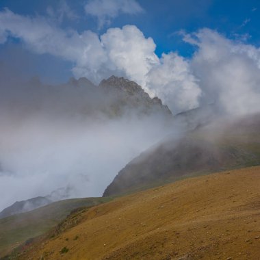 Yoğun sis ve gölgeli dağ zincirleri, dağ yolculuğu arka planı