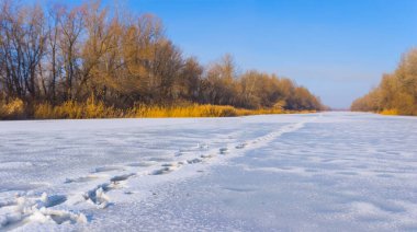 Donmuş göl, parlak kış gününde insan izleriyle kaplı karla kaplıydı.