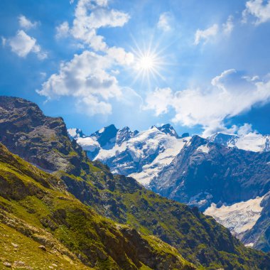 Parlak güneşin altında, karlı bir dağ vadisi.