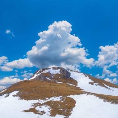 Mavi bulutlu gökyüzünün altında karlı dağ sırtı