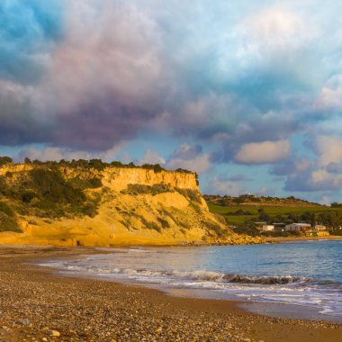 Bulutlu bir gökyüzünün altında sakin bir zümrüt koy