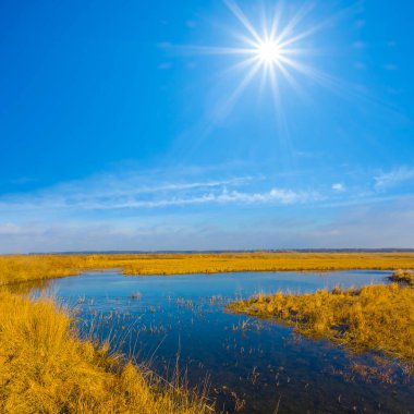 Güneşli bir günde bozkırların arasında küçük mavi bir göl.