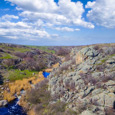 Taşlı dağ kanyonundaki nehir mavi bulutlu gökyüzünün altında