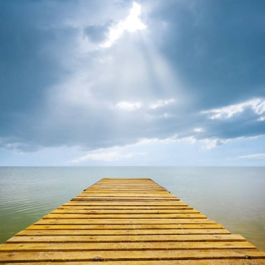 Deniz kıyısında küçük ahşap iskele dramatik bulutlu gökyüzünün altında