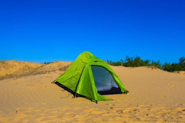 Küçük yeşil turistik çadır kumlu çölün ortasında kalıyor, ekstrem seyahat sahnesi