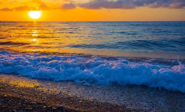 Deniz kıyıları gün doğumunda taşlarla kaplı, sabahın erken saatlerinde deniz manzarası