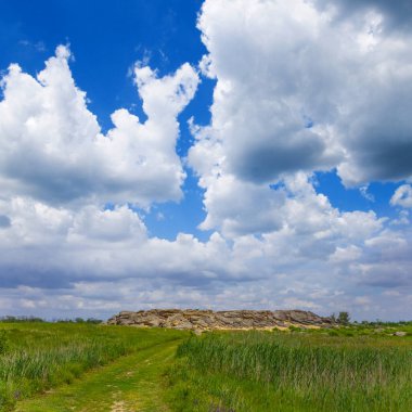 Yeşil çayırlar arasındaki taşlı tepe.