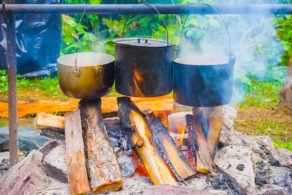 Üç turistik kazan yanıyor, yaz kampı sahnesi.