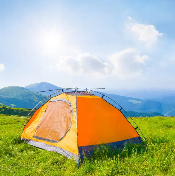 Işıl ışıl bir güneşin altında yeşil dağların arasında turistik bir çadır, yaz gezisi sahnesi
