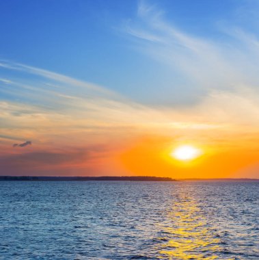 Sakin geniş bir göl üzerinde kırmızı dramatik gün batımı, güzel doğal akşam su manzarası