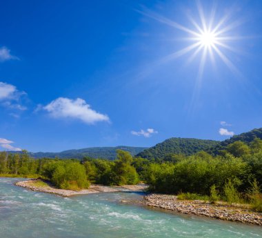 Zümrüt nehri yaz güneşli bir günde dağ vadisinde hızla akıyor.