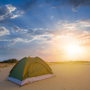 Kapalı küçük turistik çadır dramatik günbatımında kumlu çölde kalır