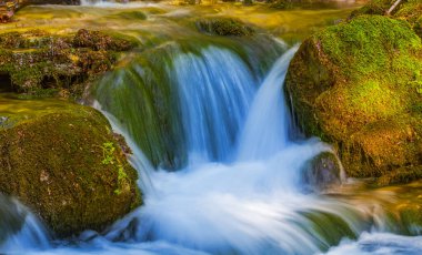 Dağdaki derede küçük bir şelale taşların üzerinden akıyor.