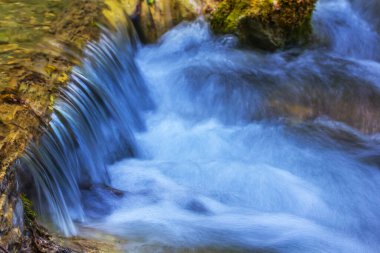 Dağdaki derede küçük bir şelale taşların üzerinden akıyor.