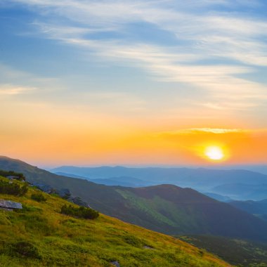 Gün batımında bulutlar içinde yeşil dağ vadisi, yaz dağ yolculuğu sahnesi