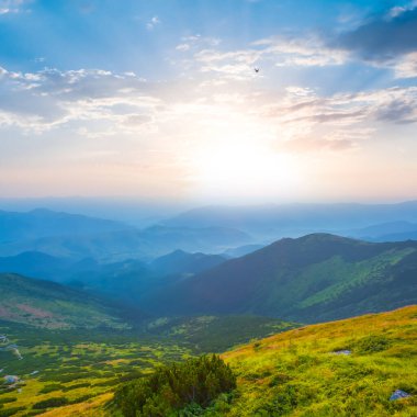 Yeşil dağ vadisi bulutların içinde gün doğumunda, yaz sabahı dağ yolculuğu sahnesinde