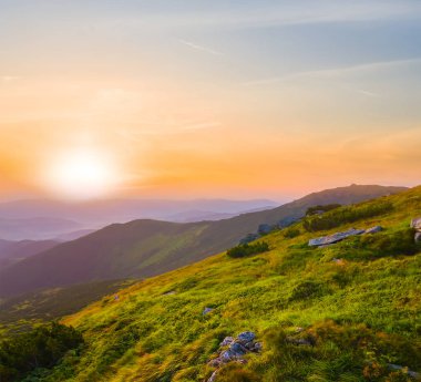 Gün batımında bulutlar içinde yeşil dağ vadisi, yaz dağ yolculuğu sahnesi