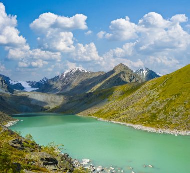 Dağ vadisindeki zümrüt göl yaz gününde mavi bulutlu gökyüzünün altında