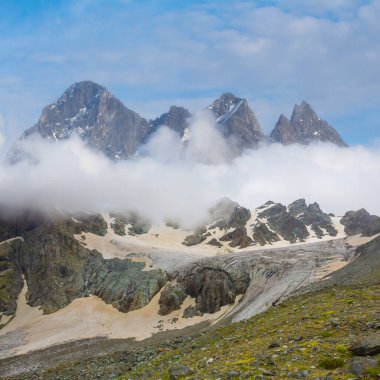 Karlı dağlarda buzullar yoğun bulutlar altında mavi bulutlu gökyüzünün altında.