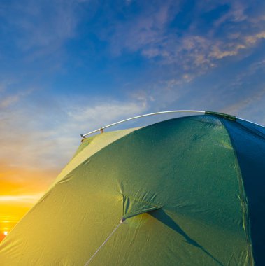 Günbatımında yakın çekim yeşil turistik çadır, kavramsal seyahat ekipmanları arka planı