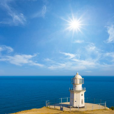 Yalnız beyaz deniz feneri yaz güneşli bir günde deniz pelerininde kalır.