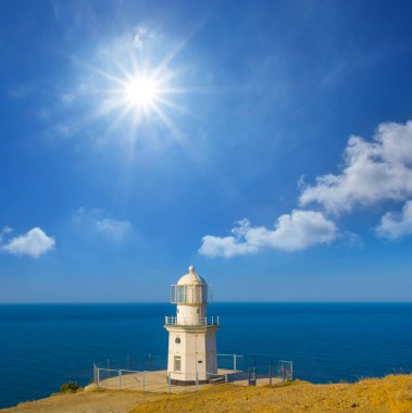 Yalnız beyaz deniz feneri yaz güneşli bir günde deniz pelerininde kalır.